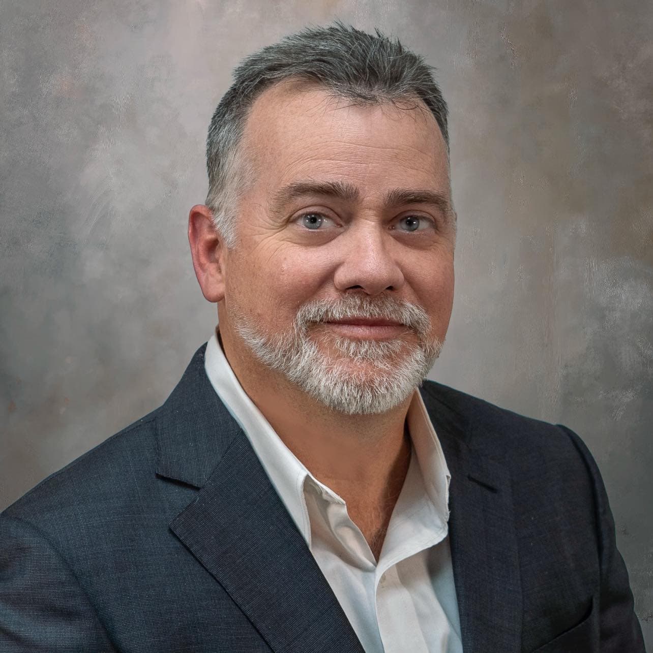 Headshot of James Barnes in gray blazer